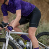 road cyclist wearing axiom halter bib short and purple motion jersey and linear socks 