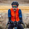 Gravel cyclist wearing orange vest and arm warmers 