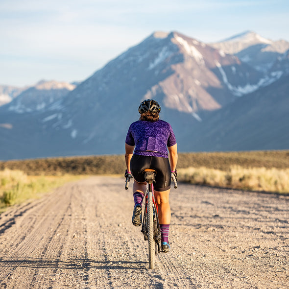 female gravel cyclsit on long road wearing purple linear socks
